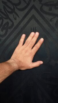 A man is touching the Holy Kaaba at Masjid al-Haram in Makkah, Saudi Arabia.