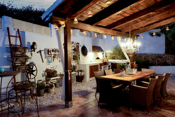 Dining table on the outdoor terrace in the evening. wooden furniture, rustic wall decorations, evening light..