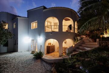 White villa at sunset, late evening, warm window lighting.