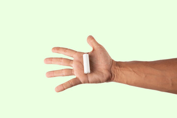 Male hand holding a white battery cell mockup on green background
