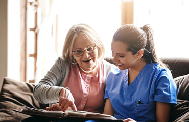 Healthcare, senior woman and nurse in lounge, photo album and nostalgia of elderly person and...
