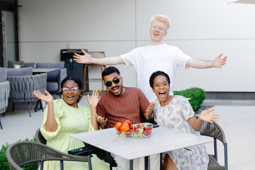 Multinational friends having fun in outdoor cafe in summer time