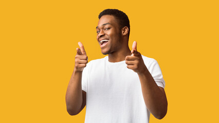 Hey, You. Positive black guy pointing fingers at camera posing over orange background, panorama,...