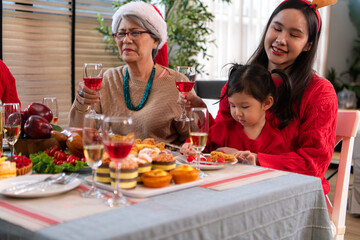 Family members are toasting with wine and drinks while sharing a meal together during the Christmas celebration at home