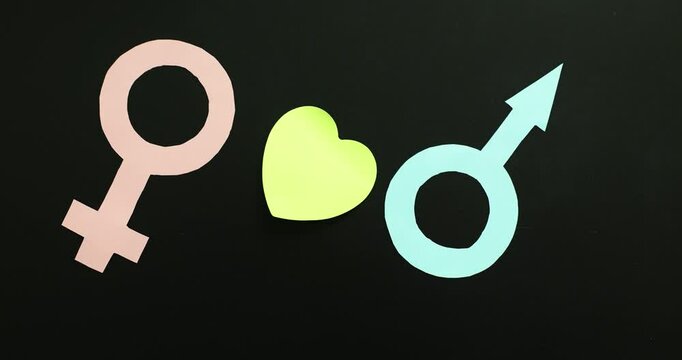 Paper heart between female and male icon on black background. Relationships and romantic feelings between man and woman