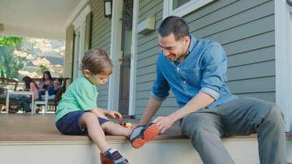 Father And Son Sit On Porch Of House Playing With Toys Together © Monkey Business