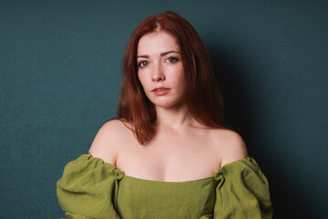 woman with long red hair wearing vinatge green off-the-shoulder dress with puff sleeves