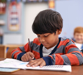 Desk, writing and boy in class for education in growth, child development and notebook for math test. Problem solving, learning and students with exam notes, knowledge and study at elementary school