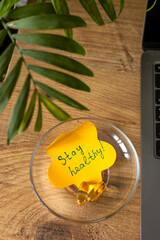 A colorful note encourages wellness placed on a clear dish surrounded by vibrant greenery