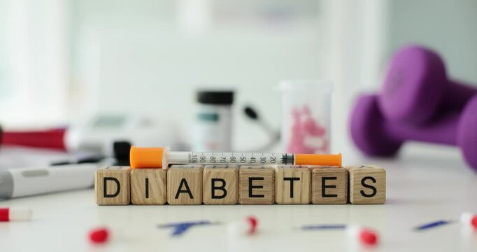 Word diabetes with insulin syringe lancet and pills on table in clinic. Insulin in treatment of diabetes