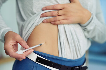 Healthcare, injection and stomach of woman with insulin treatment for hyperglycaemia in home....