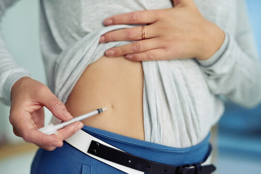Healthcare, injection and stomach of woman with insulin treatment for hyperglycaemia in home. Medical, wellness and girl with syringe for diabetes, hypertension or health management for self care