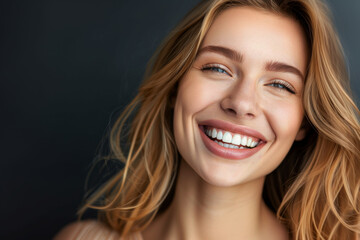 Naklejka premium Close-up portrait of a smiling beautiful female in a dark background