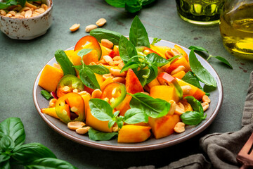 Foodie food salad with peach, hot chili peppers, peanuts and basil, green background, top view