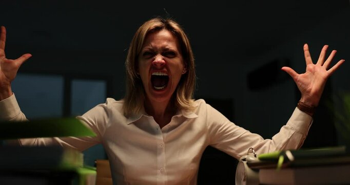 Angry aggressive business woman screaming at office desk late at night during thunderstorm. Emotions of anger aggression and fear