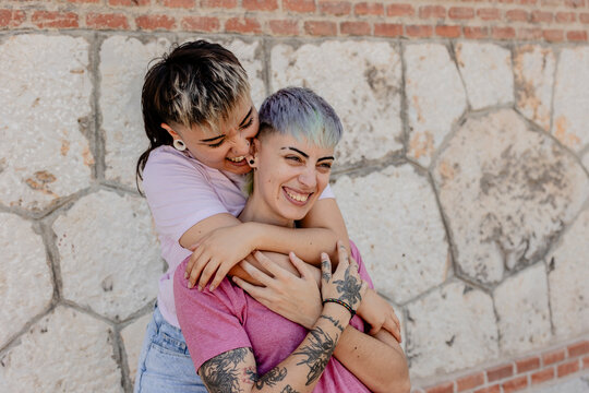 Affectionate lesbian couple embracing by a textured wall