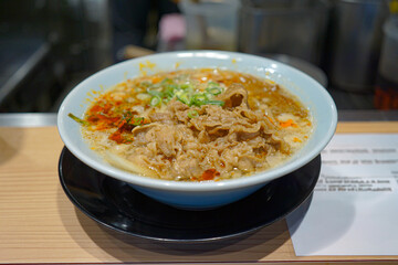 Close up ramen soup with noodles and meat in white bowl at ramen restaurant.