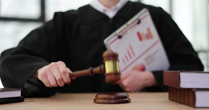 Judge knocks gavel and holds statistical papers with diagrams and graphs. Decision on financial crimes and courts