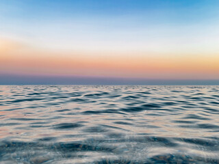 Fototapeta premium Calm sea under a blue sky at sunrise. warm tones. waterline. waves. ripples. sea water surface. 