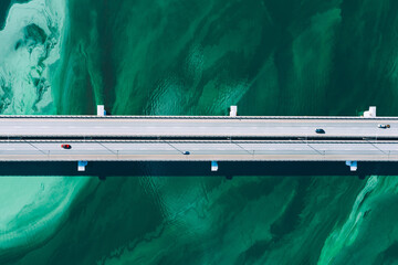 Aerial drone view of asphalt road bridge with cars and truck over turquoise blue water river sea...