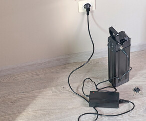 Charging bicycle battery from mains electricity in house. Socket in room with plug switched on....