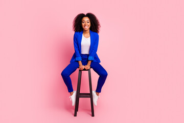 Photo of adorable lovely girl wear trendy blue clothes sit wooden stool isolated on pink color...