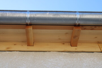 Gouttière zinc gris sur la façade de la maison, descentes rondes et sous-face en lambris bois