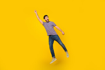 Full length body photo of young adult bearded man jumping flying in windy weather with parasol...