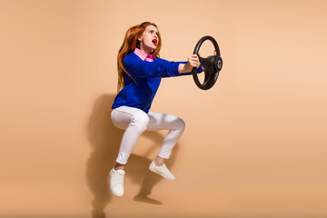 Full length portrait of pretty young lady hold wheel jump wear sweater isolated on beige color background