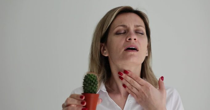 Portrait of sick girl with problems in throat with cactus. Woman holding her neck and sore throat