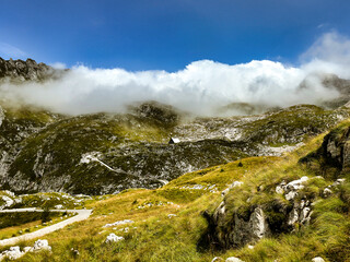 Fototapeta premium mountain valley under the clouds. lonely mountain hut. lush greenery. mountain landscape. in the clouds. nature background. Log pod Mangartom