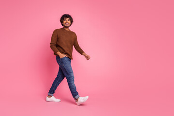 Photo of good mood cheerful man wear stylish brown clothes walk empty space isolated on pink color...