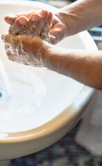 Close-up of hands washing with soap under running water at the sink.