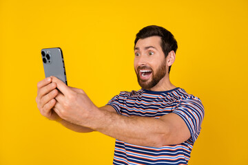 Portrait of astonished guy with bristle wear striped t-shirt staring at smartphone make selfie...
