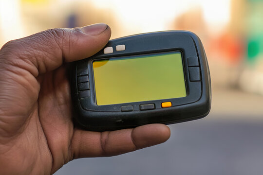 male hand holds pager, blurred Middle Eastern street in background