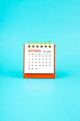 September 2025 white desk calendar on blue background.