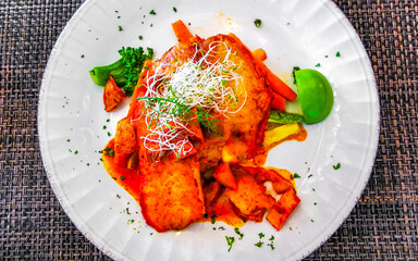White plate with a fish fillet vegetable potato dish Mexico.