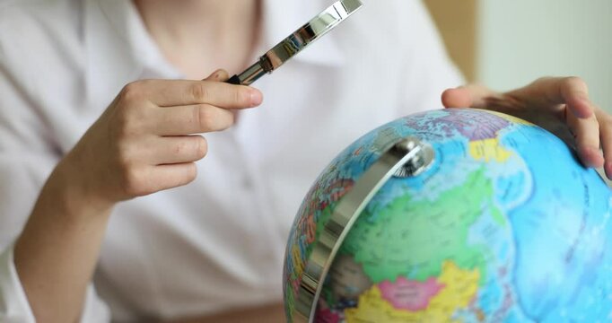 Tourist looks at world globe with magnifying glass. World tourism and search for exotic places