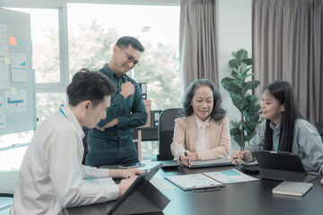 Group of Asian business people in conference room for business presentation or seminar. Documents have financial or marketing figures, graphs and charts. There is a laptop to analyze company stocks.