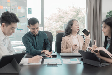 Group of Asian business people in conference room for business presentation or seminar. Documents have financial or marketing figures, graphs and charts. There is a laptop to analyze company stocks.