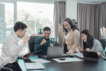 A diverse group of business professionals gather at a conference table in an office to celebrate a business victory, a good sales result, and achieving a financial goal.
