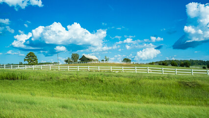 Beautiful meadow under blue sky and white cloud. A peaceful view of country side with white fence,...