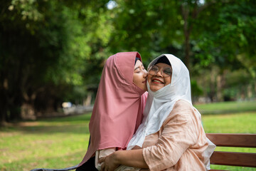 Muslim careful caregiver or nurse taking care of the patient in the hospital park. Happy Muslim mother in hijab hugging daughter. Concept of Savings and Senior Health Insurance, a Happy Family