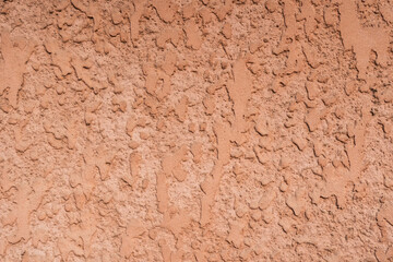 A detailed close-up of a rough orange wall surface, showcasing its unique texture and patterns. This image is ideal for use in graphic design, architectural projects, or as a background texture for va
