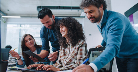 Intelligent Caucasian managers helping their coworker with project. Curly woman working at computer...