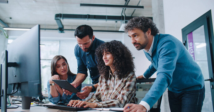 Group of smart Caucasian coworkers intently looking at computer screen. People brainstorming about working plan or searching for solution to issue. Men and women positively communicating.