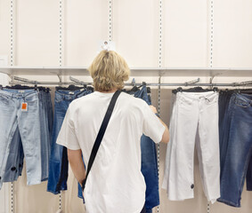 young man choosing clothes in a shopping mall. clothes hangers