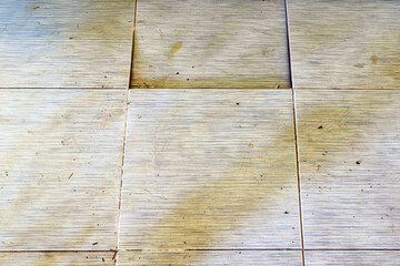 Background with falling off tiled tiles in living room. Close up of cracked ceramic tiles on a...