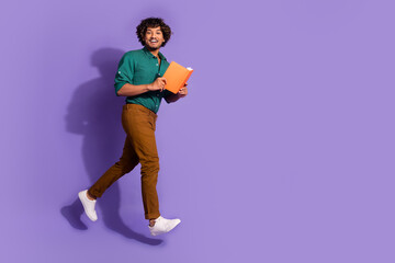 Photo of jumping young clever mexican man university student in green shirt reading study materials isolated on violet color background