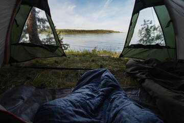 Wild camping in nature. Aegna island on a summer morning. View from a tent on the seashore, sleeping bag.